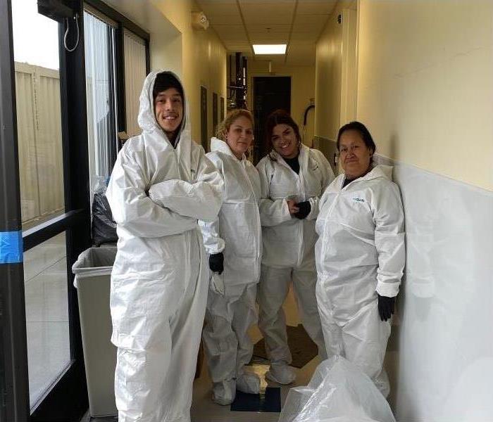 Three people standing while wearing protective clothing 